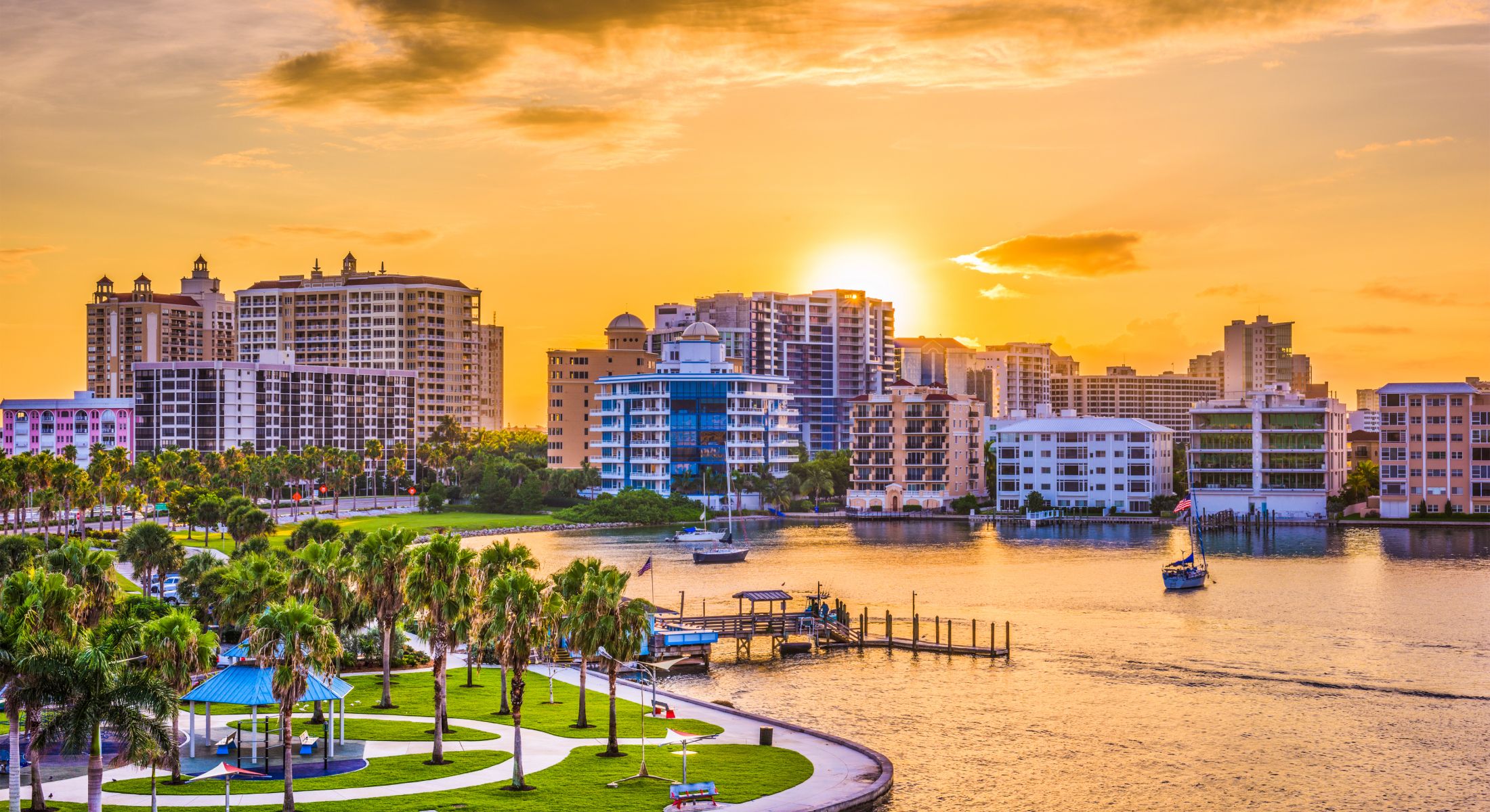 Sunset over waterfront city skyline and park.